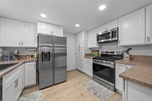 kitchen with stainless steel appliances, light wood-type flooring, white cabinetry, a sink, and recessed lighting