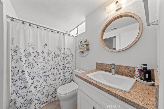 bathroom featuring visible vents, a shower with shower curtain, toilet, a textured ceiling, and vanity