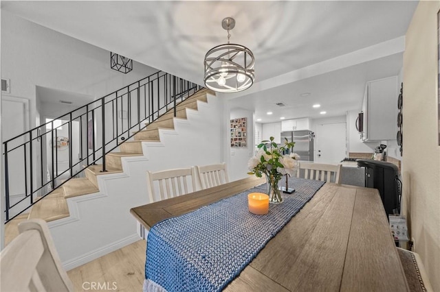 dining space with baseboards, light wood-style flooring, stairs, a chandelier, and recessed lighting