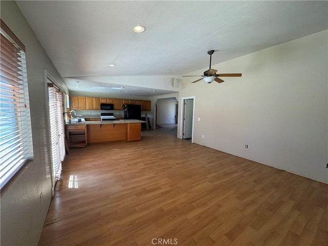 kitchen featuring brown cabinets, light countertops, visible vents, open floor plan, and black appliances