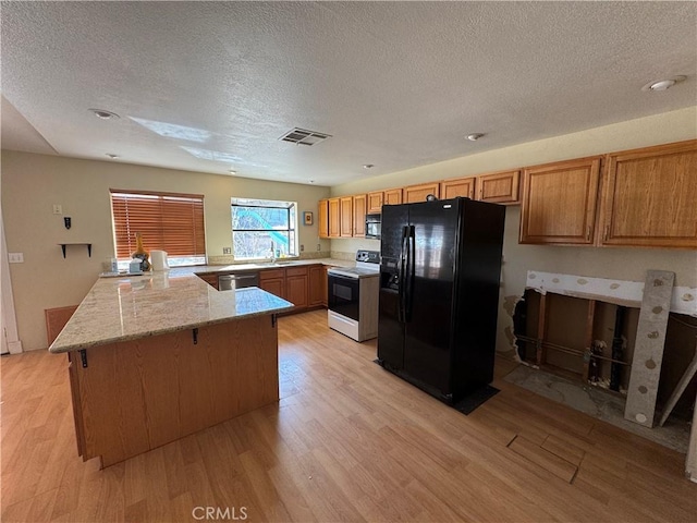 kitchen featuring a peninsula, black appliances, visible vents, and light wood-style floors