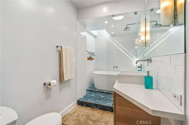 full bathroom featuring a soaking tub, vanity, and toilet