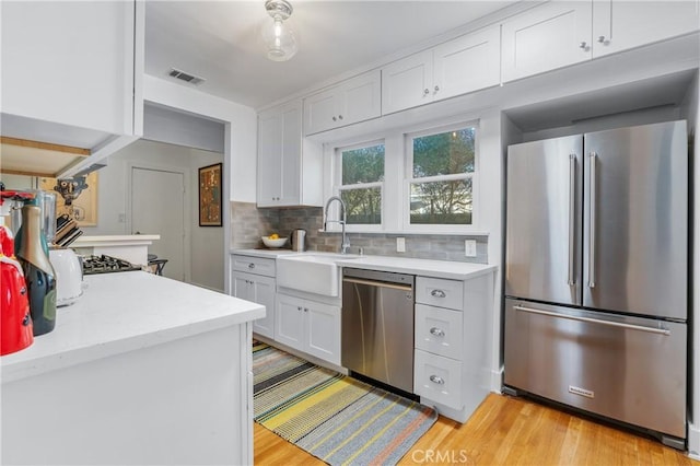 kitchen featuring light countertops, backsplash, appliances with stainless steel finishes, white cabinetry, and a sink