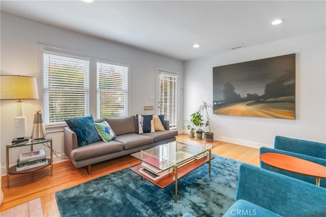 living area with recessed lighting, visible vents, baseboards, and wood finished floors