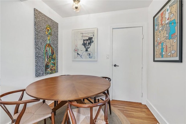 dining space with light wood finished floors, breakfast area, and baseboards