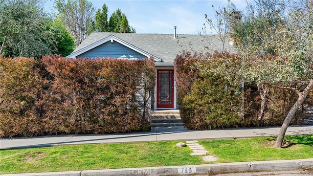 obstructed view of property featuring a shingled roof and a front lawn