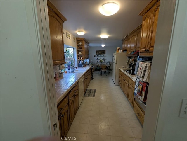 kitchen featuring brown cabinets, tile countertops, open shelves, a sink, and white appliances