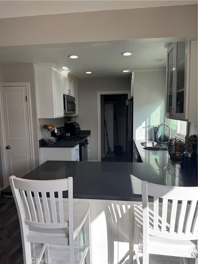 kitchen with white cabinets, range with gas stovetop, stainless steel microwave, freestanding refrigerator, and a sink