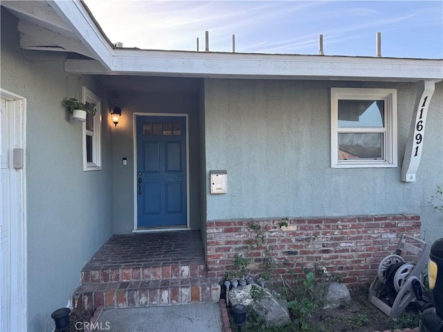 property entrance featuring brick siding and stucco siding