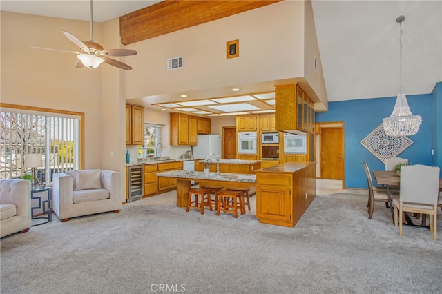 kitchen featuring wine cooler, white appliances, a kitchen island, open floor plan, and light countertops