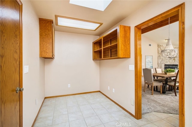 spare room featuring light carpet, light tile patterned floors, baseboards, and vaulted ceiling