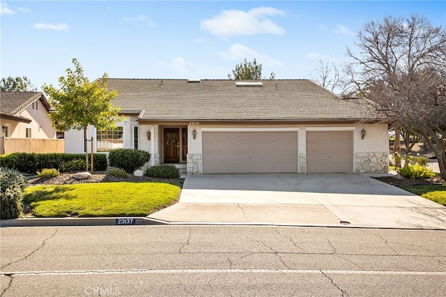 view of front of property featuring concrete driveway, stone siding, a tiled roof, an attached garage, and stucco siding