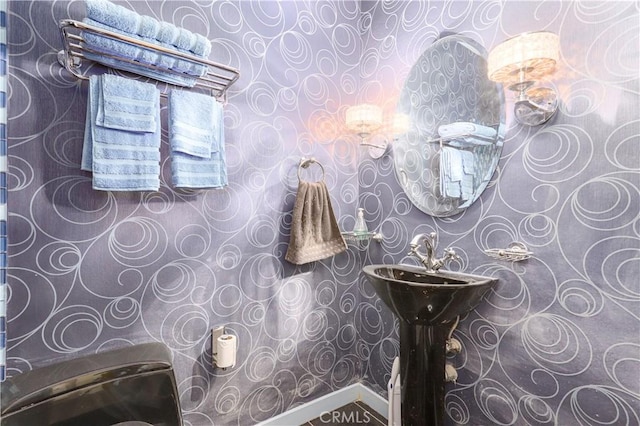 half bathroom featuring wallpapered walls and baseboards