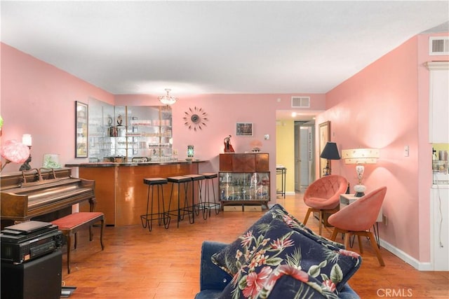 living area with light wood-type flooring, visible vents, and baseboards