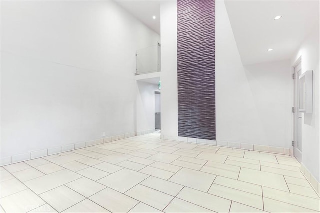 interior space with recessed lighting, a towering ceiling, baseboards, and light tile patterned floors