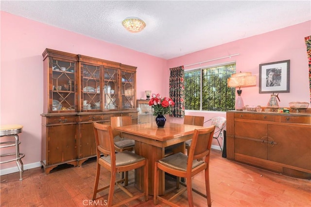 dining area featuring a textured ceiling, baseboards, and wood finished floors