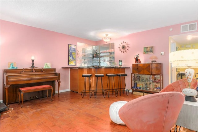 living area with baseboards, visible vents, a bar, and wood finished floors