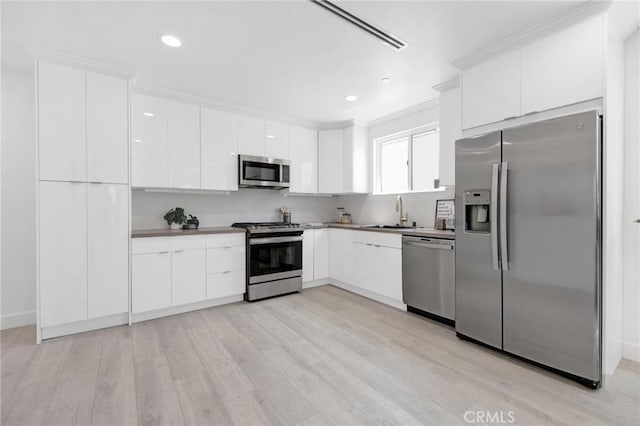 kitchen featuring appliances with stainless steel finishes, modern cabinets, a sink, and white cabinets