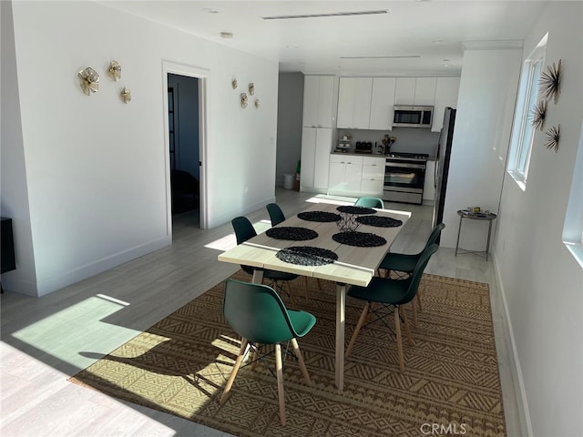 dining area with light wood-type flooring and baseboards