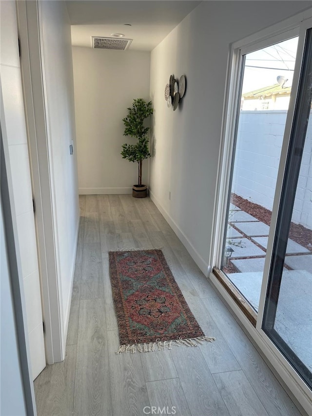 hallway featuring baseboards, visible vents, and light wood-style floors