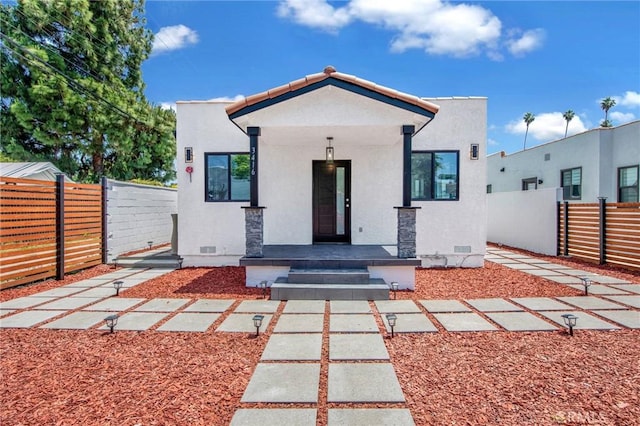 rear view of house featuring crawl space, a fenced front yard, and stucco siding