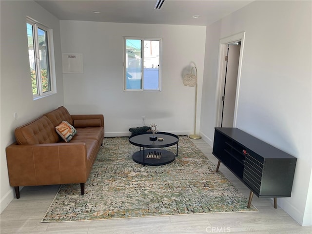 living area featuring light wood-style floors, a wealth of natural light, and baseboards