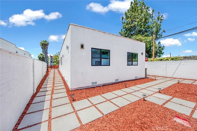 view of property exterior featuring crawl space, a fenced backyard, and stucco siding