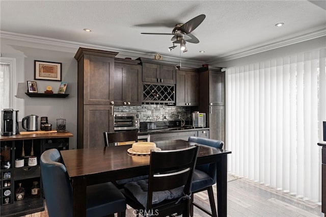 kitchen featuring a ceiling fan, ornamental molding, and dark brown cabinets