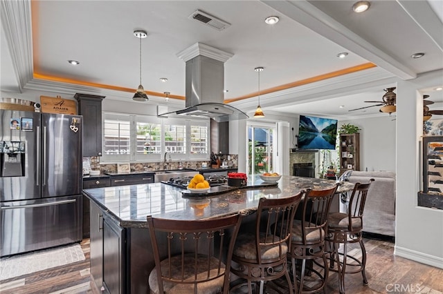 kitchen featuring ornamental molding, island exhaust hood, a kitchen island, visible vents, and appliances with stainless steel finishes