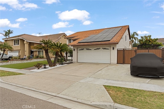 view of front of property with stucco siding, a tile roof, concrete driveway, and solar panels