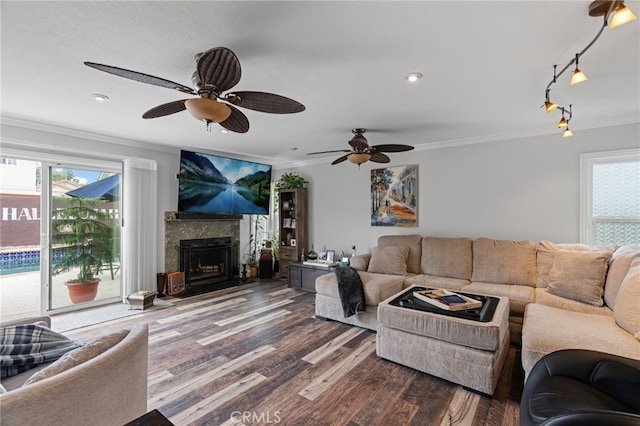 living area with wood finished floors, ornamental molding, and a healthy amount of sunlight