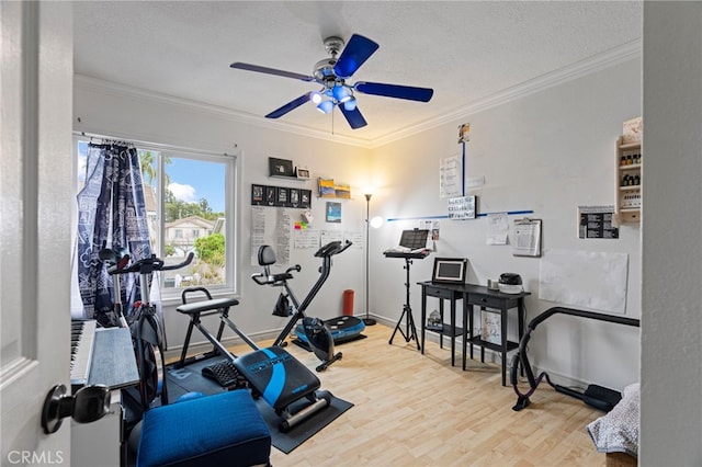 exercise room featuring a textured ceiling, wood finished floors, ornamental molding, and a ceiling fan