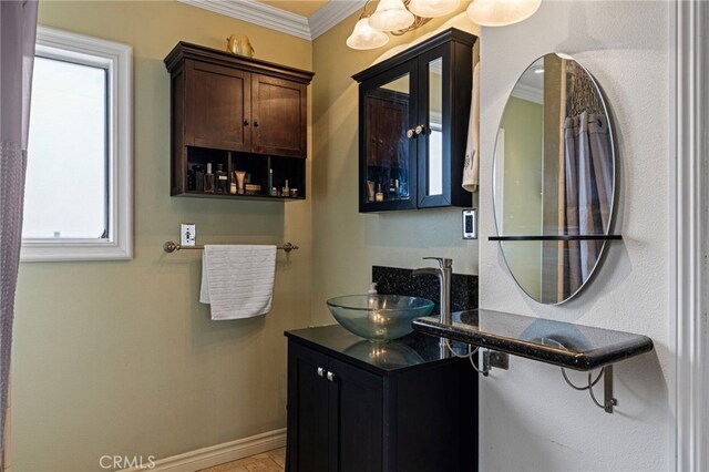 bathroom with vanity, crown molding, and baseboards
