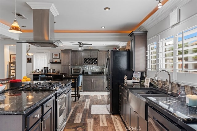 kitchen with ornamental molding, island exhaust hood, visible vents, dark brown cabinets, and appliances with stainless steel finishes