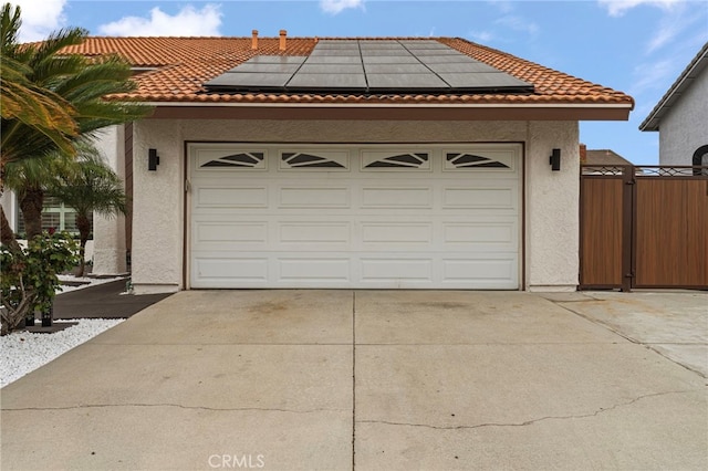 garage with concrete driveway and roof mounted solar panels