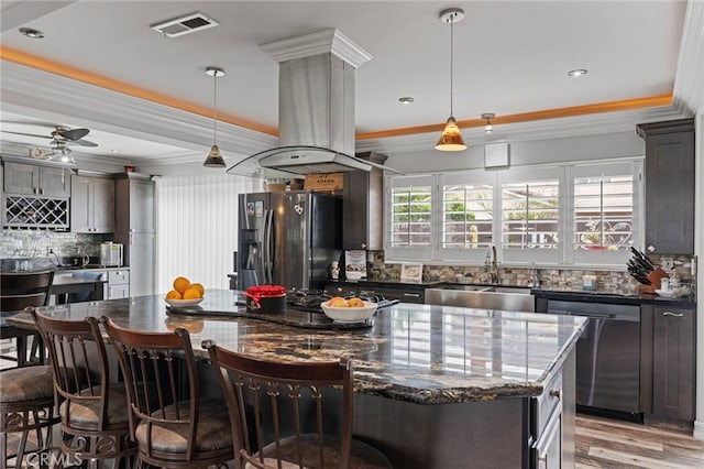 kitchen with crown molding, island exhaust hood, refrigerator with ice dispenser, a sink, and dishwasher