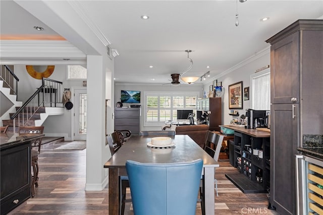 dining area featuring dark wood-style flooring, ceiling fan, ornamental molding, and beverage cooler