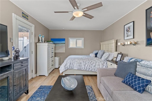 bedroom with radiator heating unit, multiple windows, light wood-style flooring, and a ceiling fan