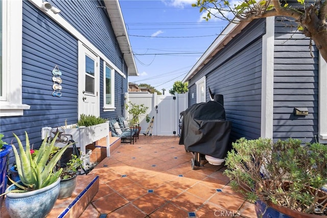 wooden deck with a gate, a patio, grilling area, and fence