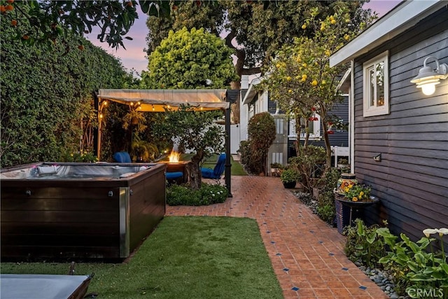 yard at dusk with a fire pit, a patio, a hot tub, and a pergola