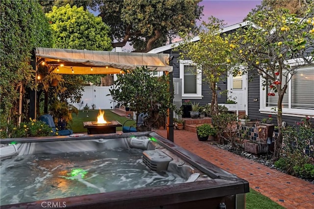 view of patio / terrace featuring an outdoor fire pit and a hot tub