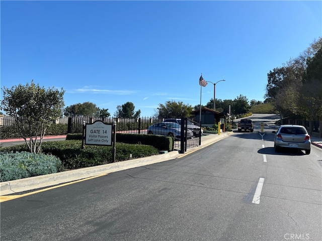 4018 Calle Sonora Este Unit C, Laguna Woods, CA 92637 - view of asphalt road with curbs, street lights, and a gated entry