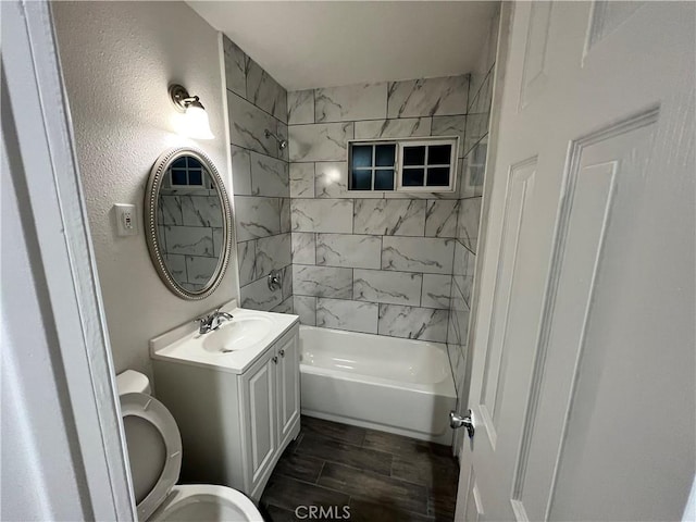 bathroom with bathtub / shower combination, a textured wall, toilet, wood tiled floor, and vanity