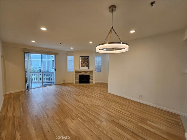 unfurnished living room featuring light wood-type flooring, a fireplace, baseboards, and recessed lighting