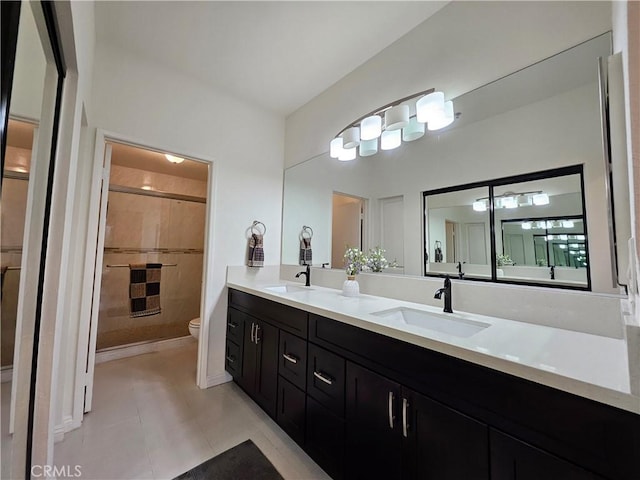 bathroom featuring toilet, a shower stall, double vanity, and a sink