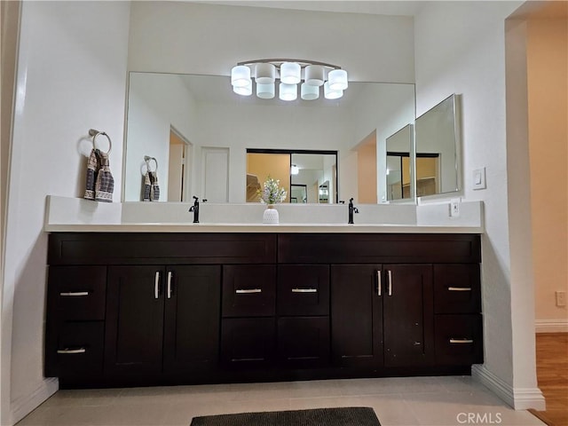 full bath featuring a sink, baseboards, and double vanity