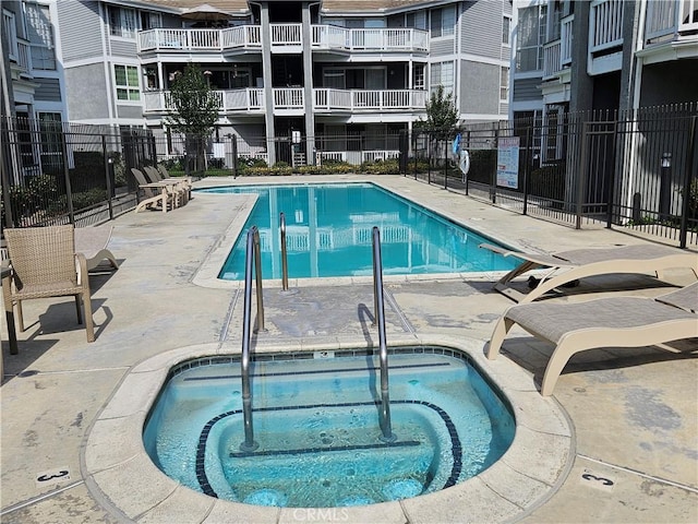 view of swimming pool featuring a community hot tub and fence