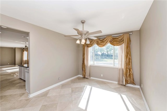 empty room featuring baseboards, a ceiling fan, and light tile patterned flooring