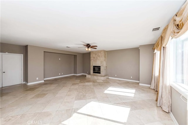 unfurnished living room with a wealth of natural light, visible vents, a fireplace, and ceiling fan