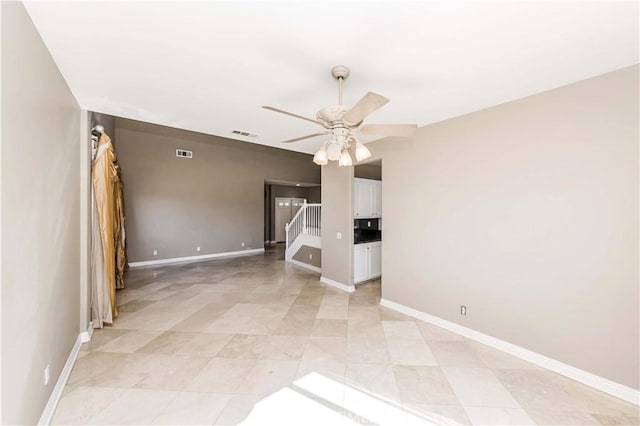 unfurnished living room with baseboards, stairs, visible vents, and a ceiling fan